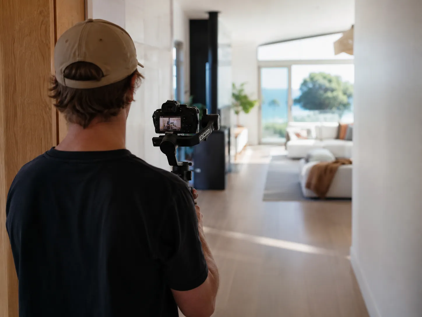 Videographer filming a walkthrough of a home with a gimbal-mounted camera